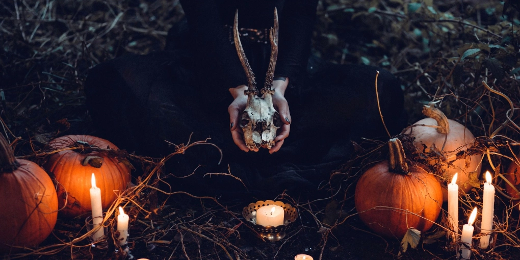 Witch holding a skull surrounded by occult paraphanalia